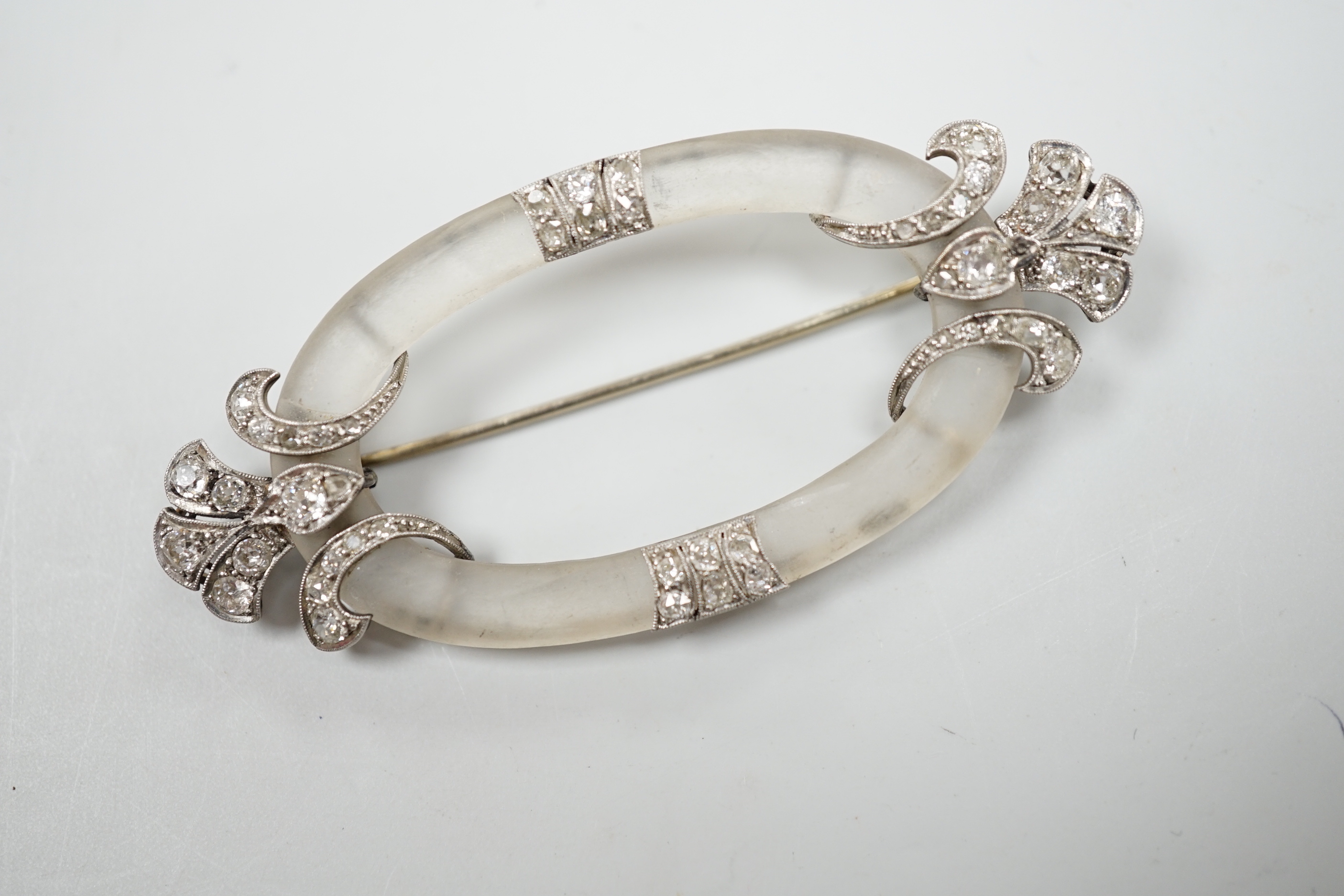 A Belle Epoque diamond set platinum and frosted brooch of open oval form with stylised foliate terminals, width 7cm